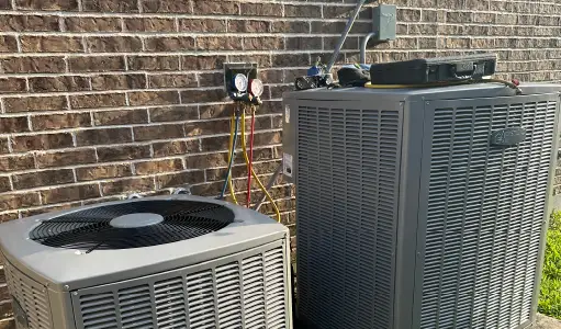 Two outdoor condensers against Texas brick with a manifold gauge set hung on the wall